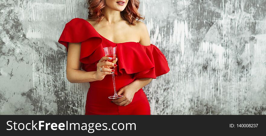 Smiling woman in red dress with a glass of champagne. Party concept