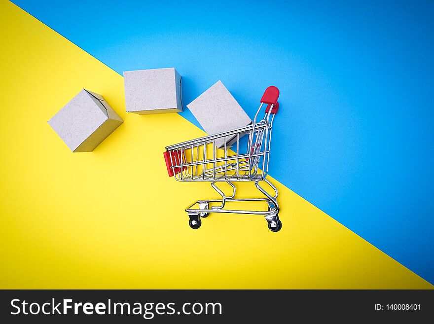 Shopping cart and box on blue and yellow background, business and shopping concept. Selective focus