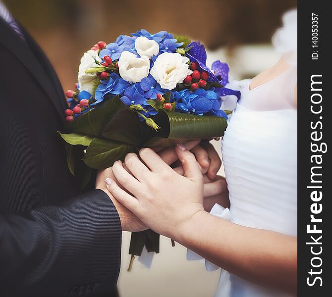 The Bride And Groom Are Holding A Bouquet Of Flowers.