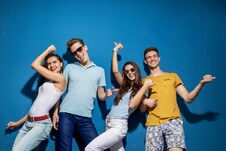 Four Good-looking Friends Are Laughing While Standing In Front Of The Blue Wall Having Confident And Happy Looks Royalty Free Stock Photography