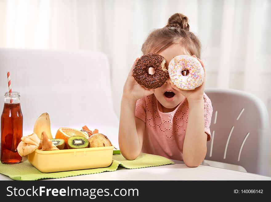 Little beautiful cheerful girl eating a donut