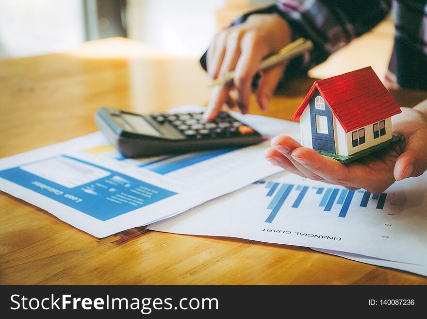 Woman holding house model in hand and calculating financial chart for investment to buying property