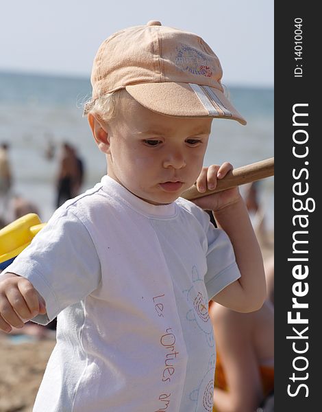 Young kid playing on the beach with his hat and t-shirt on. Young kid playing on the beach with his hat and t-shirt on
