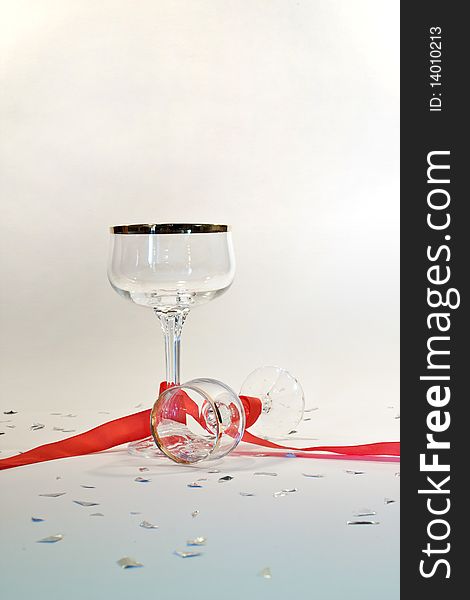 Picture of two glasses with gold edge  on a party table with red ribbon and silver chads. Picture of two glasses with gold edge  on a party table with red ribbon and silver chads