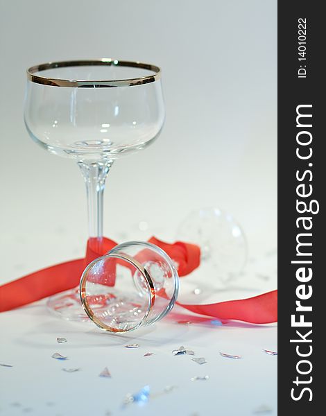 Picture of two glasses with gold edge  on a party table with red ribbon and silver chads. Picture of two glasses with gold edge  on a party table with red ribbon and silver chads