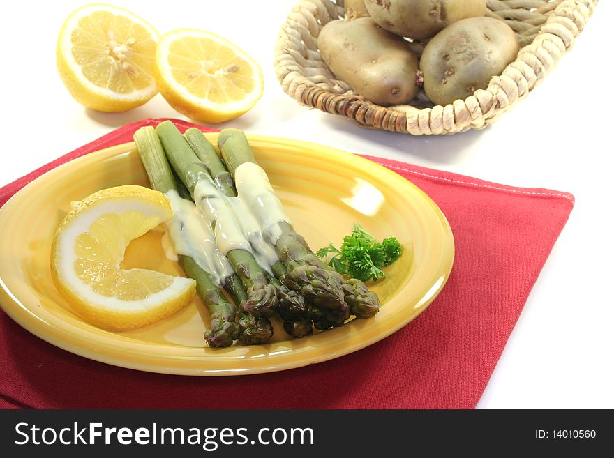 A bundle of green asparagus with lemon hollandaise sauce on a white background. A bundle of green asparagus with lemon hollandaise sauce on a white background