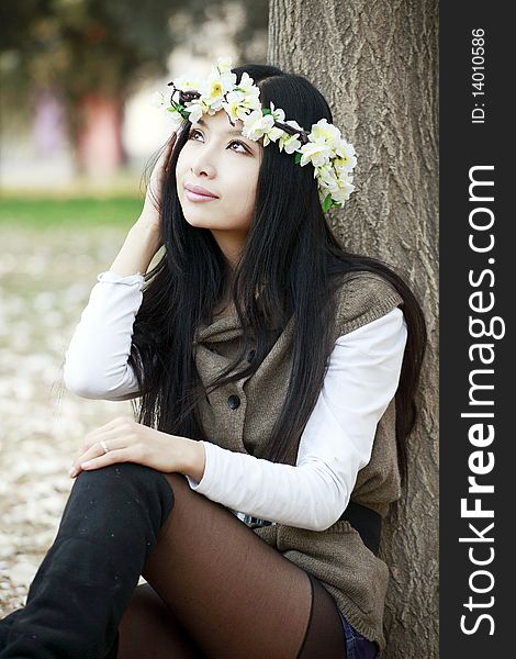 Asian smile girl sitting under the tree in spring.she is enjoying the spring scenery. Asian smile girl sitting under the tree in spring.she is enjoying the spring scenery.