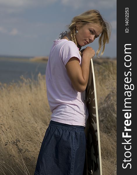 The fair-haired girl with surfboard on seacoast. The fair-haired girl with surfboard on seacoast