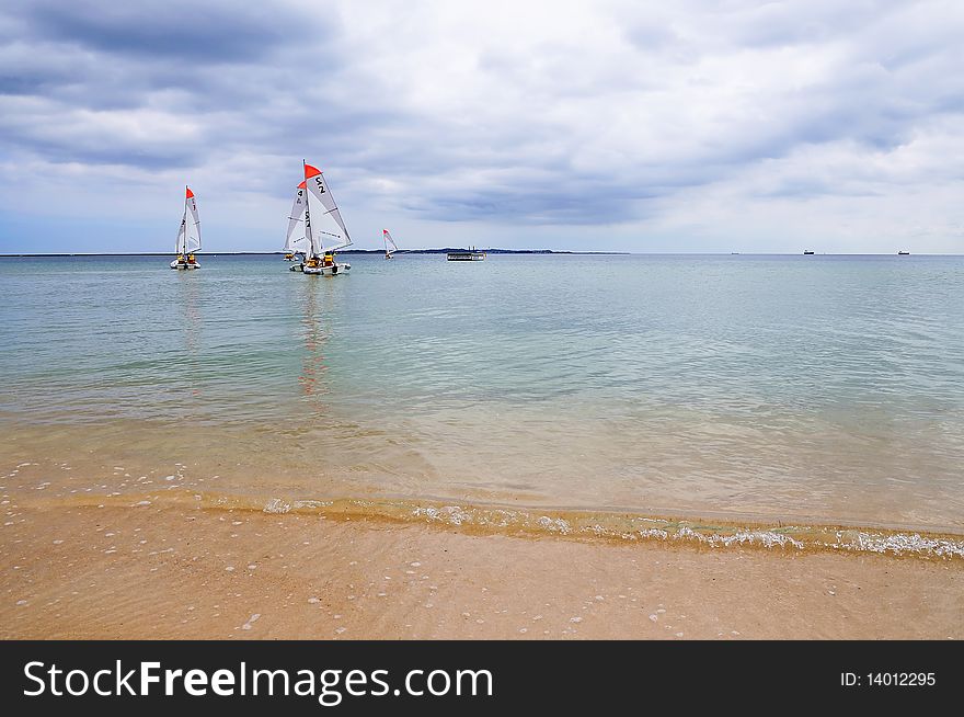 Several boats with sails floating on the ocean