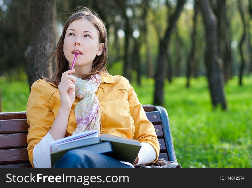 Young woman sitting on the bench and reading book. Young woman sitting on the bench and reading book