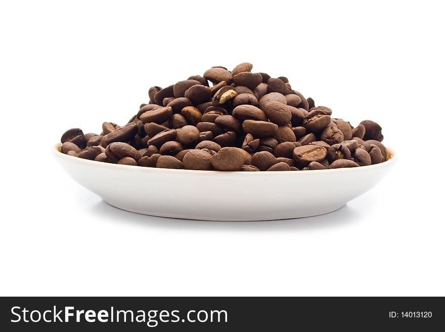 Saucer with grains of coffee on a white background