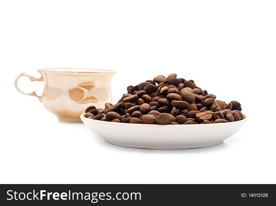 Saucer with grains of coffee on a white background