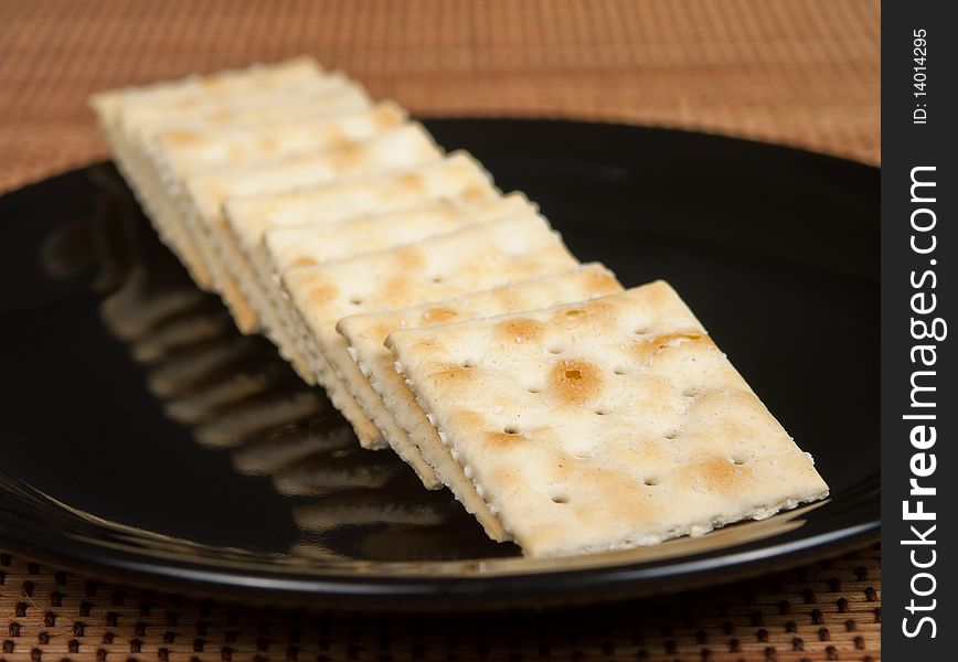 Row of Saltine Crackers on a black plate.