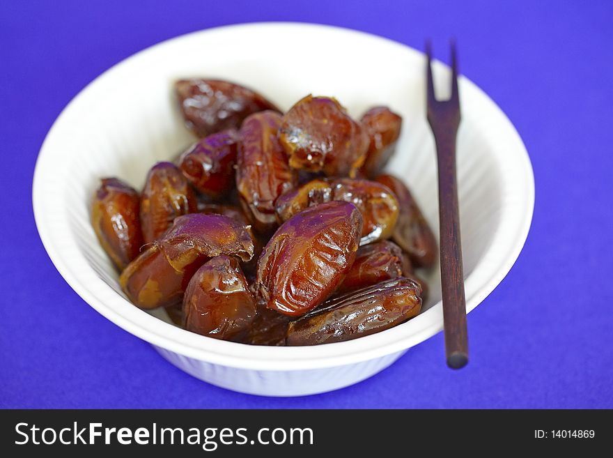 Bowl of date fruit with a wooden fork.