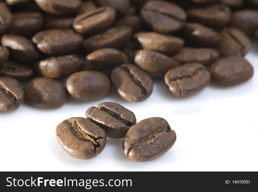 Coffee beans on white background. Closeup view with focus on three front beans. Coffee beans on white background. Closeup view with focus on three front beans.