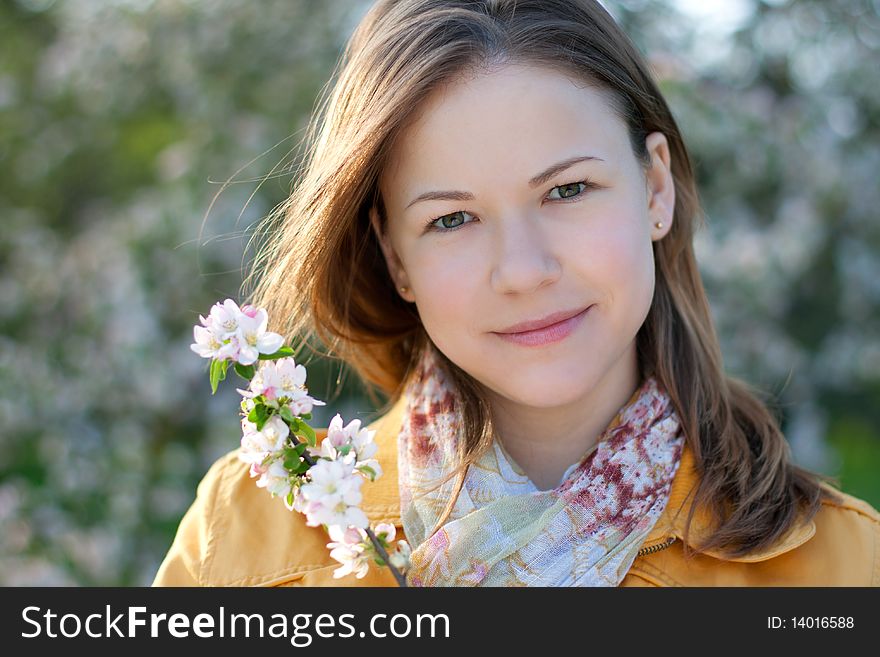 Young woman posing with a blooming branch in a spring park. Young woman posing with a blooming branch in a spring park