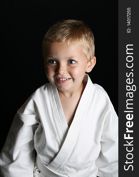 Young boy wearing his karate uniform on a black background. Young boy wearing his karate uniform on a black background