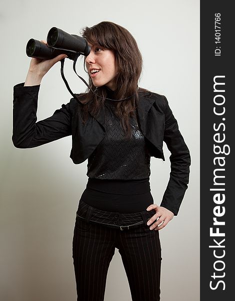 Young woman standing and holding binoculars. Young woman standing and holding binoculars