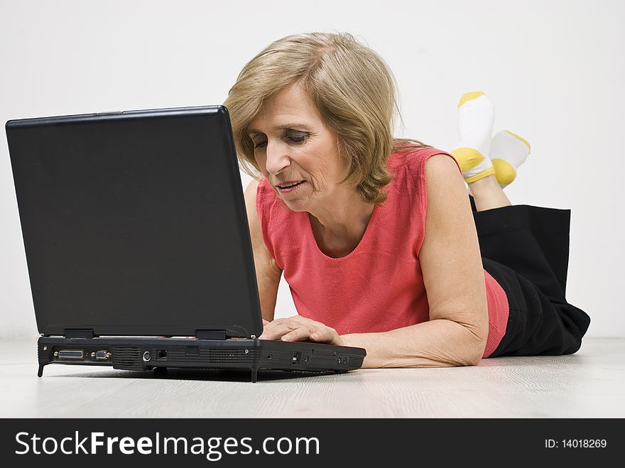 Senior woman relaxing  on floor and browsing internet on laptop,see more in <a href=http://www.dreamstime.com/people-on-couch-or-wooden-floor-rcollection11965-resi828293>People on couch or wooden floor</a>. Senior woman relaxing  on floor and browsing internet on laptop,see more in <a href=http://www.dreamstime.com/people-on-couch-or-wooden-floor-rcollection11965-resi828293>People on couch or wooden floor</a>