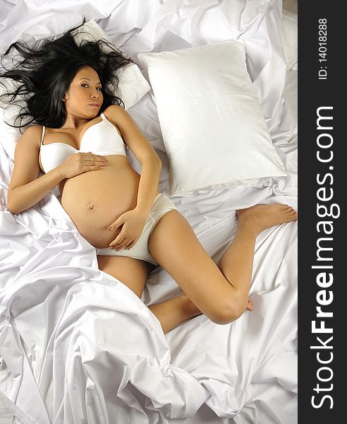 woman is pregnant and sprawled over the bed. woman is pregnant and sprawled over the bed