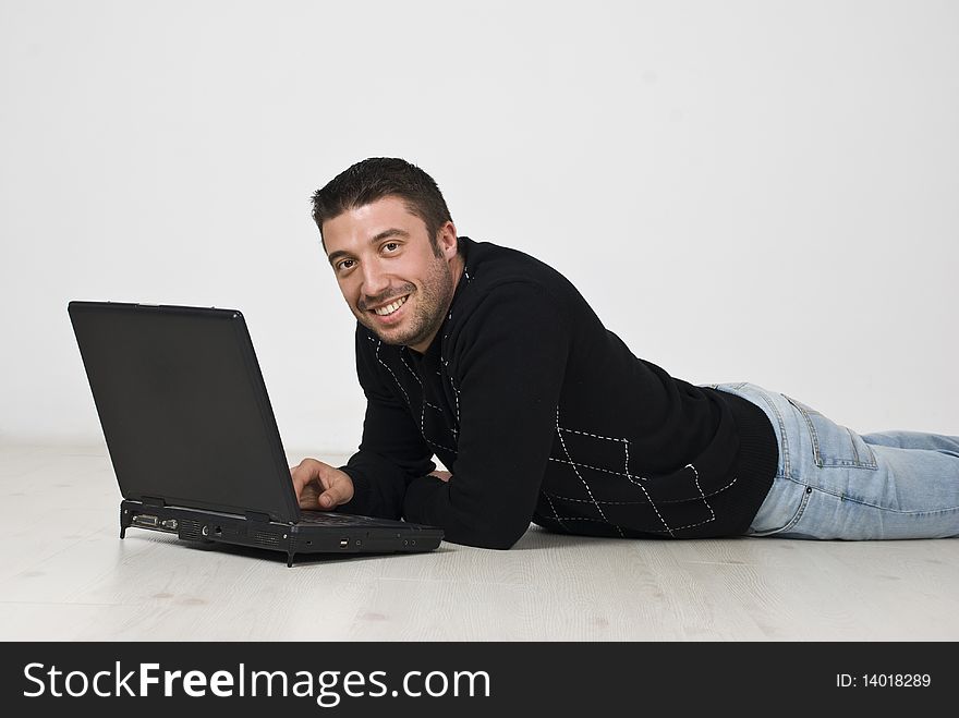 Smiling man lying on floor with laptop