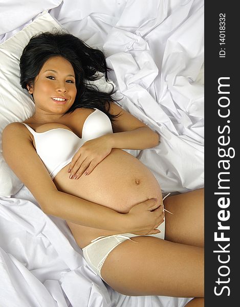 Pretty Indonesian woman is pregnant and on the bed. Pretty Indonesian woman is pregnant and on the bed
