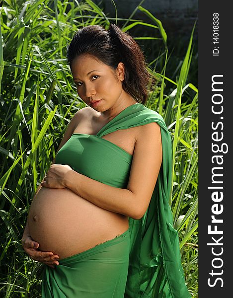 Woman poses with her unborn child outdoors. Woman poses with her unborn child outdoors