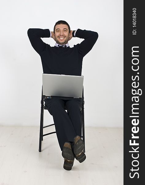 Happy businessman with laptop on chair