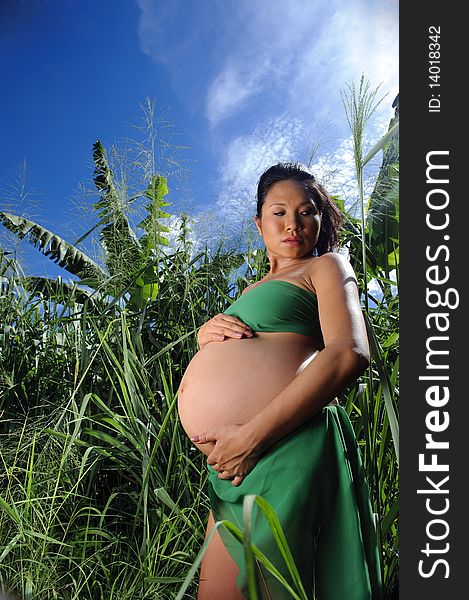 Woman is outdoor in the jungle and holds her pregnant stomach. Woman is outdoor in the jungle and holds her pregnant stomach