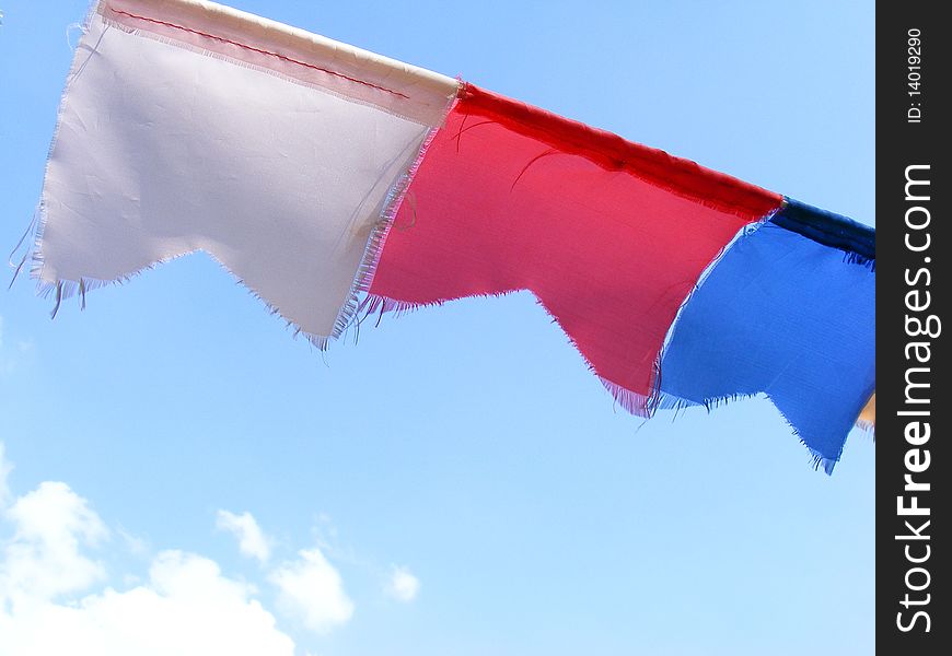 Three color flags on a wire and blue sky