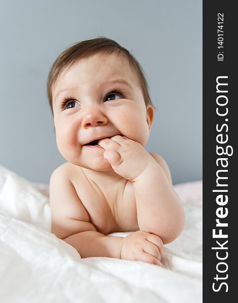 Portrait of beautiful baby lying on stomach and looking straight. Infant is. Isolated on grey background