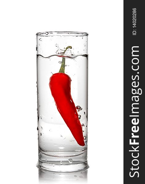 Red pepper dropped into water glass with bubbles