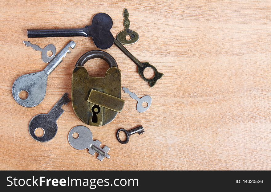 Old padlock and keys on wooden background