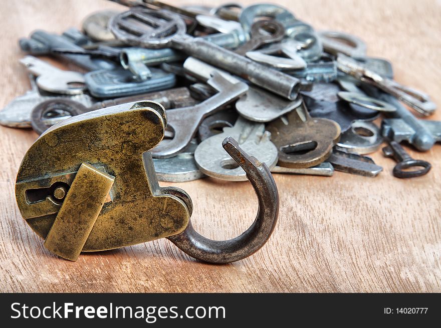 Old padlock and heap of keys on wooden background. Old padlock and heap of keys on wooden background