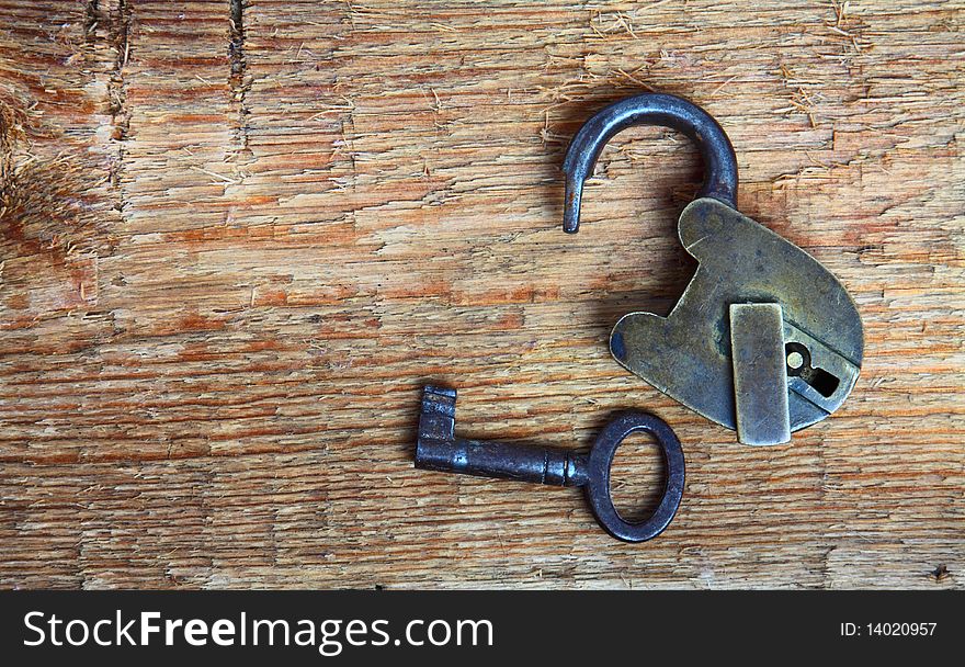 Old padlock and key on wooden background