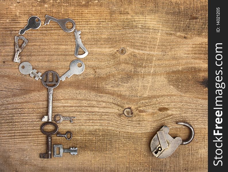 Old padlock and keys on wooden background