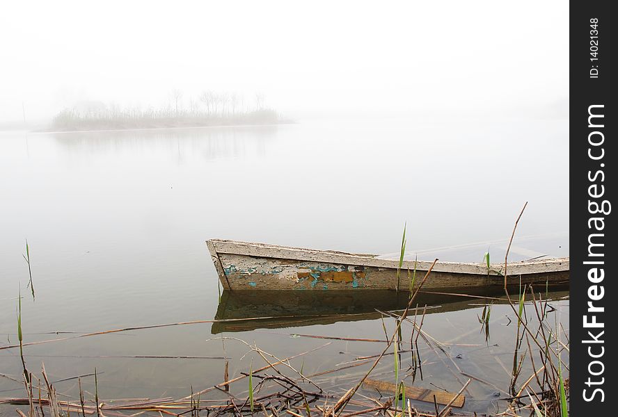 Sunken boat and tiny island in fog