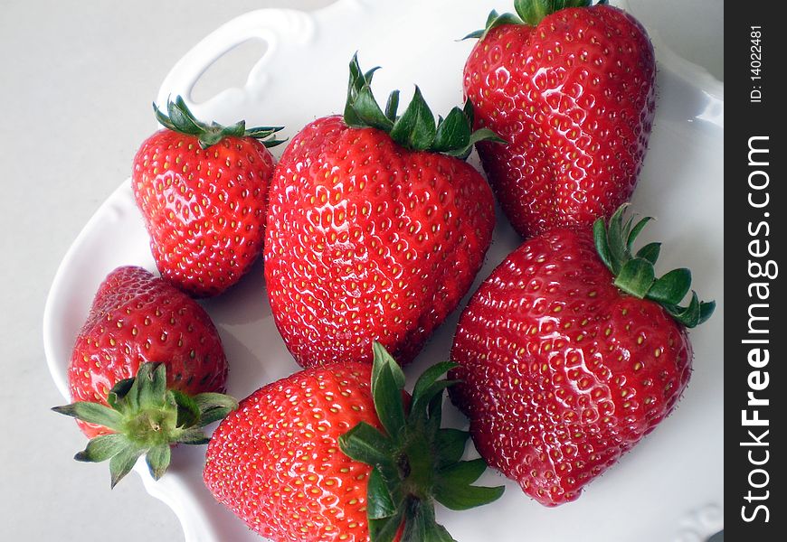 Close up view of some Strawberries on a white porcelain background