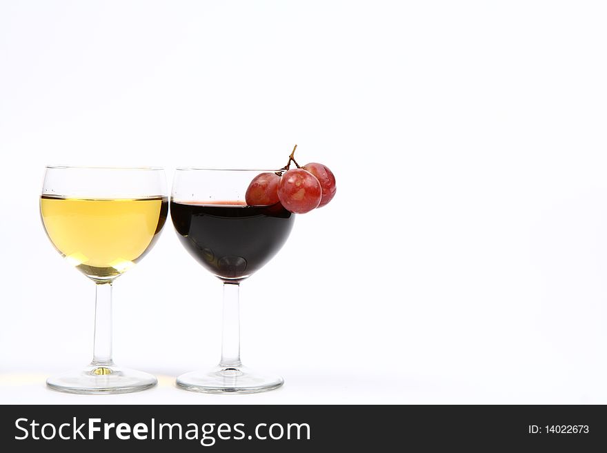 Two wineglasses of white and red wine with three red grapes and white space for text. Two wineglasses of white and red wine with three red grapes and white space for text