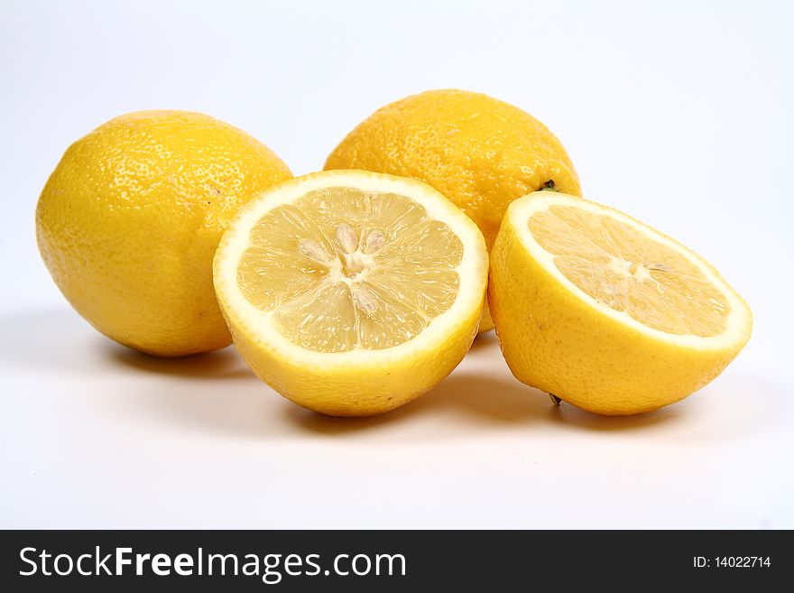 Three lemons, one cut in half, on white background