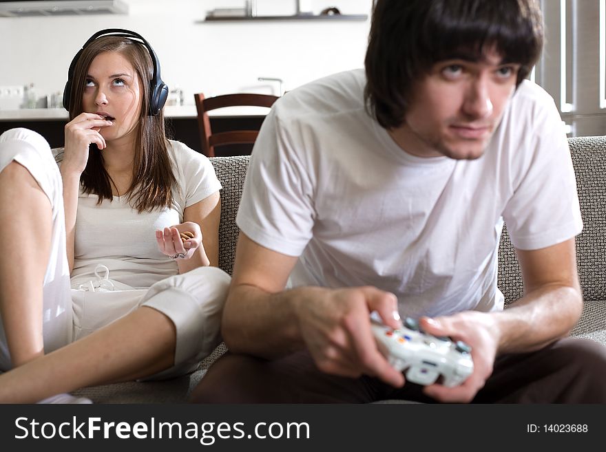 Girl with long hair in headphones and boy on sofa. Girl with long hair in headphones and boy on sofa
