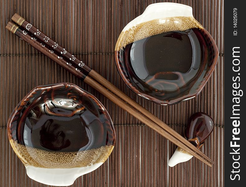 Sticks fo sushi and two porcelain plates on the brown bamboo mat. Sticks fo sushi and two porcelain plates on the brown bamboo mat