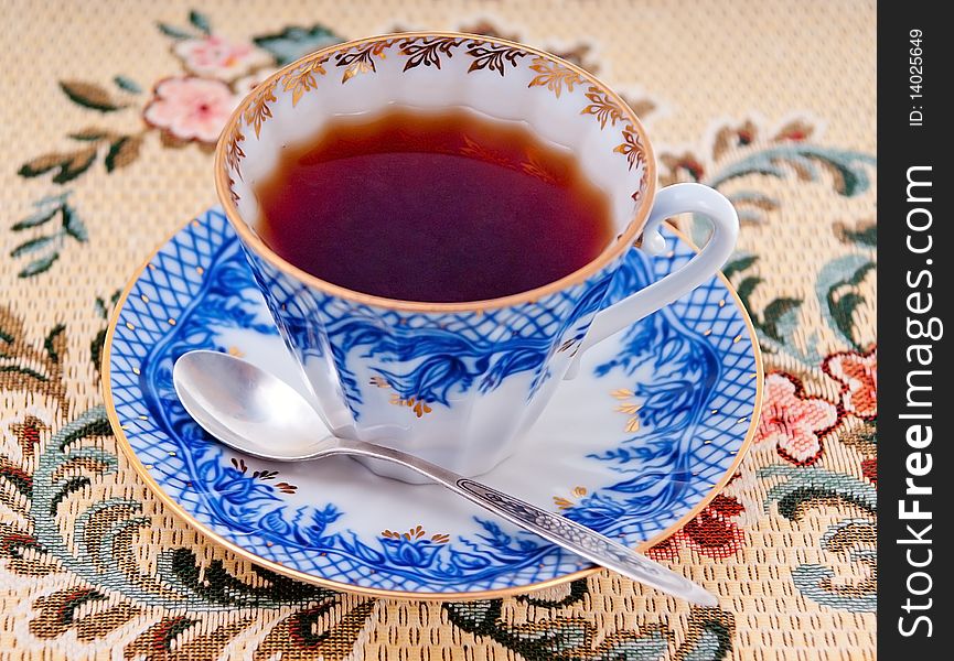 Cup with tea on a saucer and a silver teaspoon