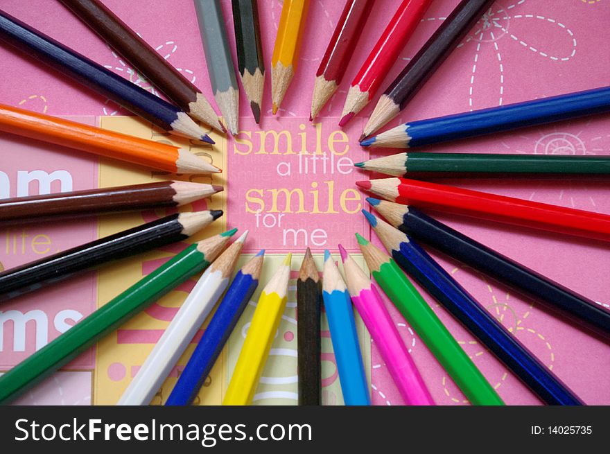 Color pencils on pink background with the inscription