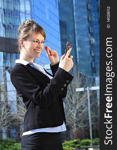 Young attractive smiling woman with a mobile cell over office building. Young attractive smiling woman with a mobile cell over office building