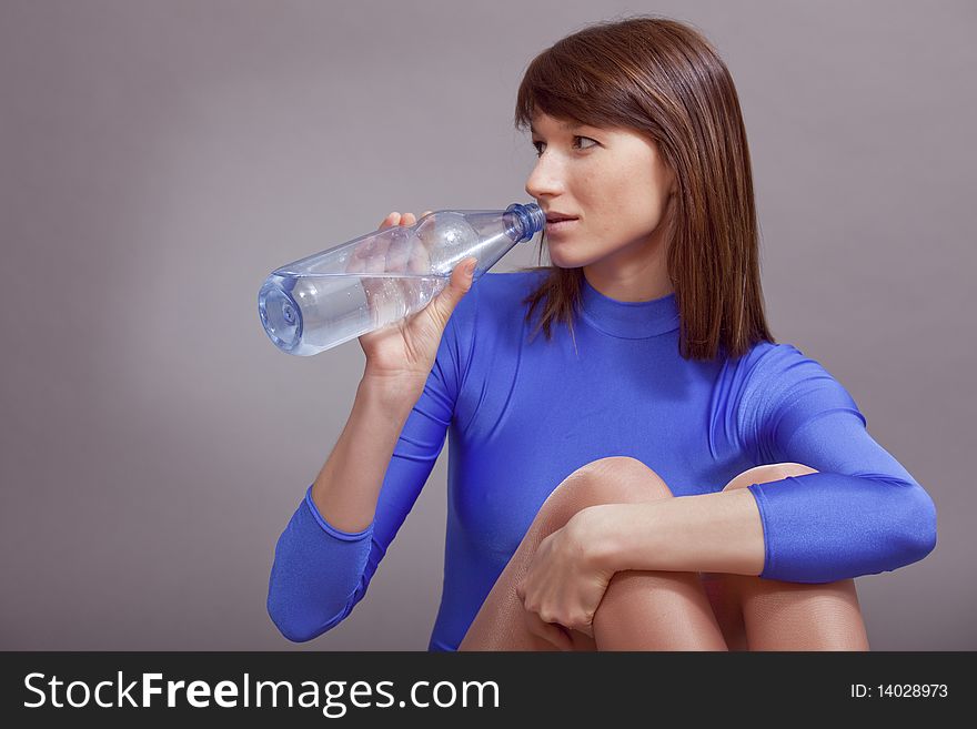 Young woman in blue leotard drinking water. Young woman in blue leotard drinking water