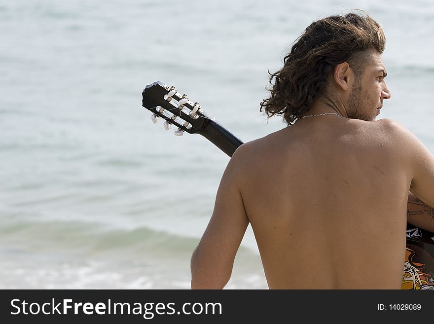 Young man playing the guitar on the beach. Young man playing the guitar on the beach