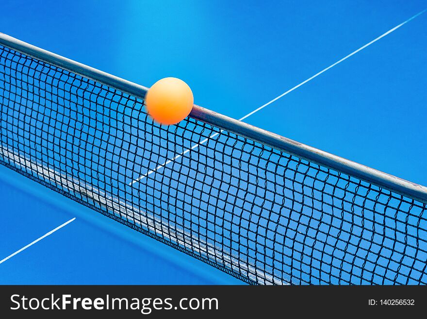 Yellow ball hits the netting on a blue pingpong table