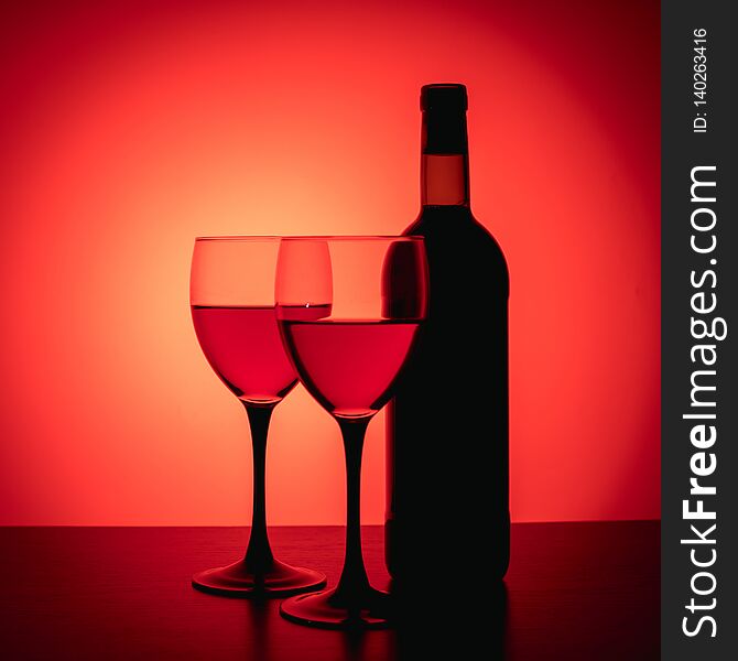 Wine glasses and bottle on red background