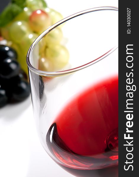 A glass of red wine and grapes on a white background. A glass of red wine and grapes on a white background